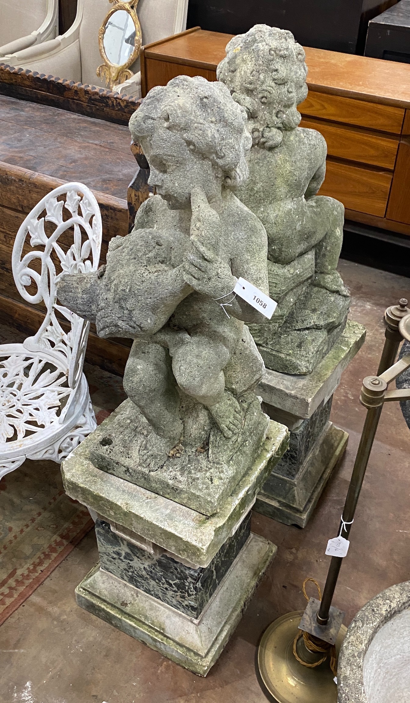 A pair of reconstituted stone cherub and dove garden ornaments on faux marble plinths, height 116cm